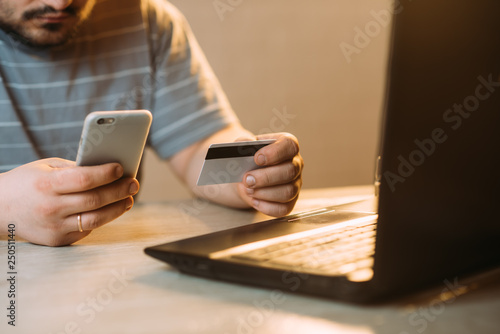 Cropped picture of man with credit card white pattern and phone photo