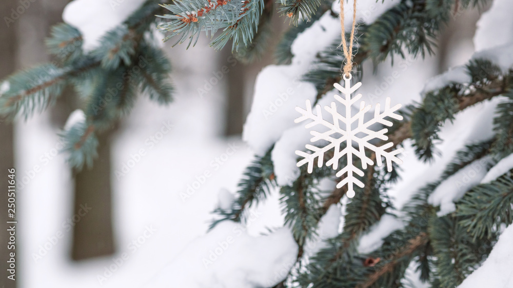 Cute decoration in the form of a wooden snowflake on a Christmas tree, outside next to the house, closeup