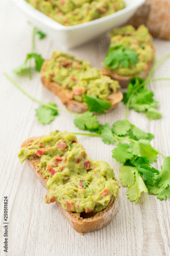 Fresh avocado cream or guacamole on wholemeal slices, healthy breakfast concept. Fresh avocado cream or guacamole on wholemeal slices, healthy breakfast concept.