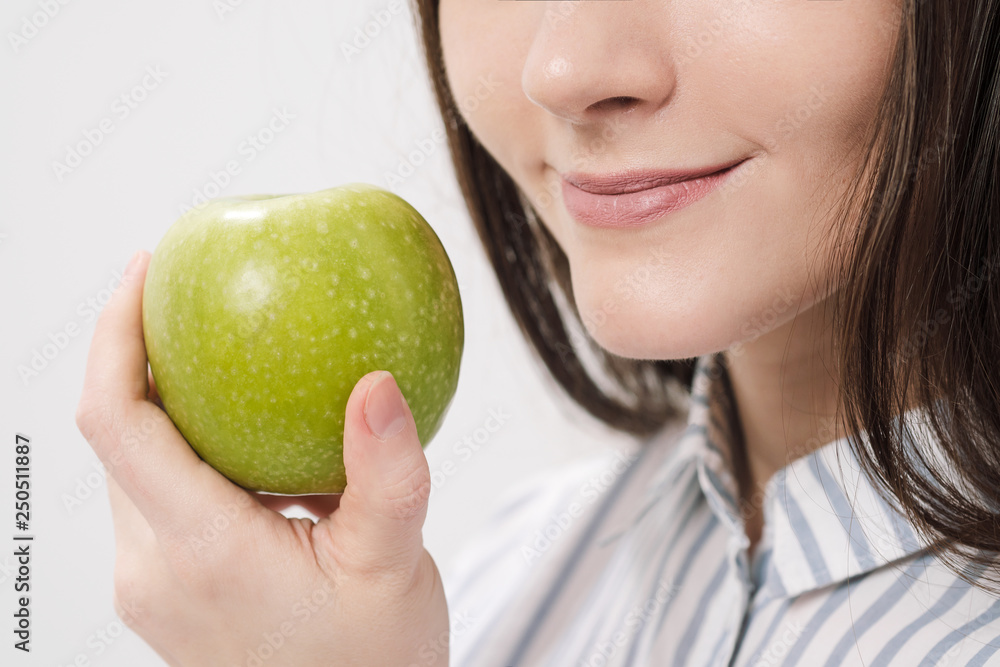 Young beautiful brunette girl on a white background holding a fresh green apple. Young beautiful brunette girl on a white background holding a fresh green apple.
