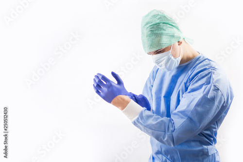 Surgeon doctor in sterile gloves preparing for operation in hospital. He is wearing surgical cap and blue gown