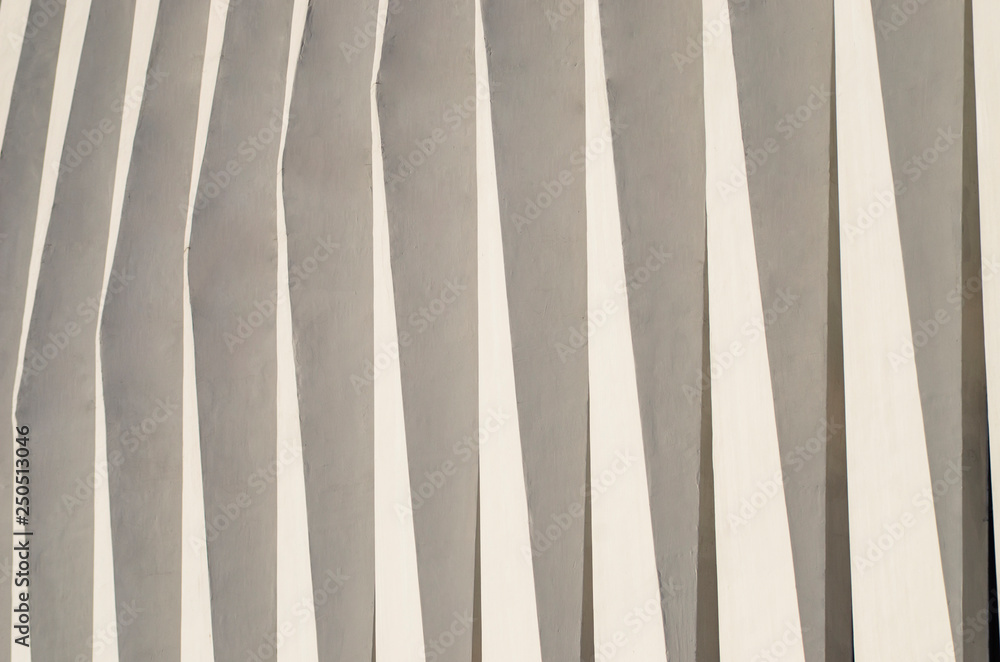 Obraz premium Wave facade of the building. White graphical linear facade of the building. The play of light and shadow. Neutral fashionable background. Light stripes.