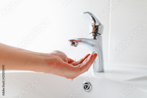 hand under faucet with low pressure water stream photo