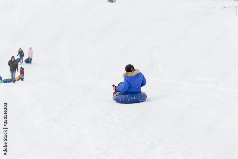 winter, leisure, sport, friendship and people concept - group of happy people sliding on the snow inflatable chambers