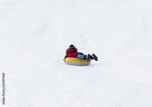 Brave child in red jackets, a trip in the winter from the mountains to tubing. He has an inflatable chamber. It slides quickly through the snow.