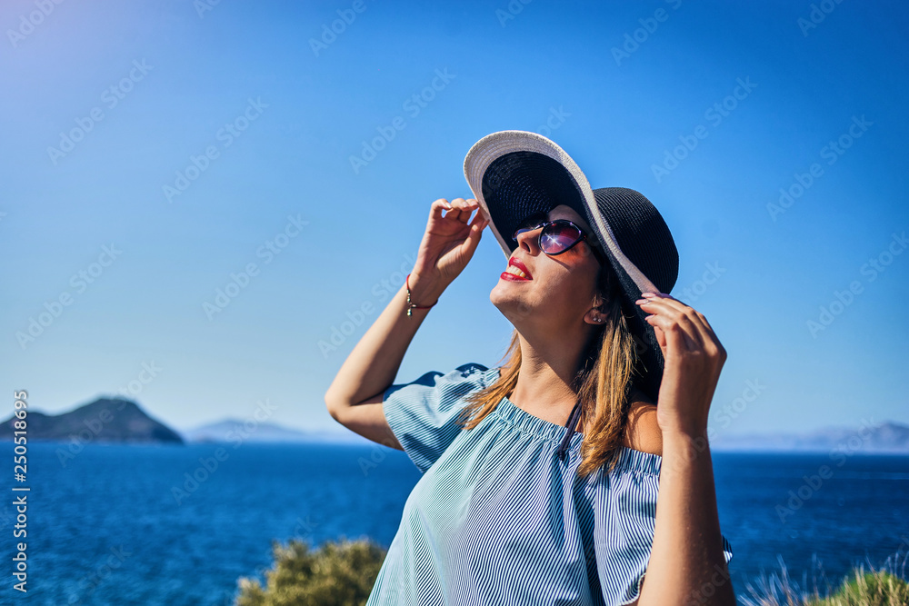 Beautiful woman in beach hat enjoying sea view with blue sky at sunny day in Bodrum, Turkey. Vacation Outdoors Seascape Summer Travel Concept Beautiful woman in beach hat enjoying sea view with blue sky at sunny day in Bodrum, Turkey. Vacation Outdoors Seascape Summer Travel Concept