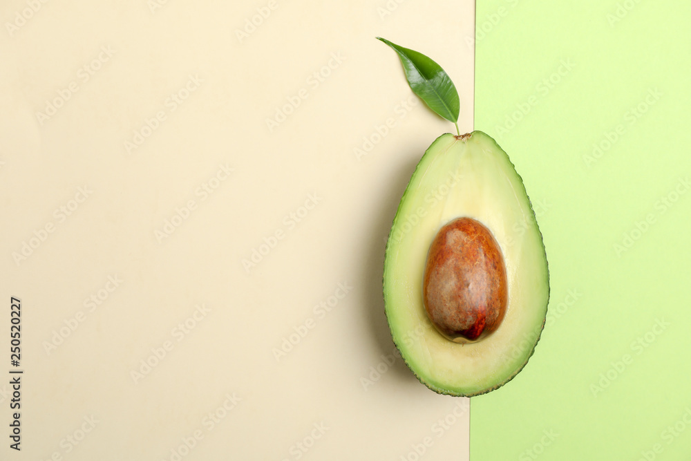 Ripe cut avocado on color background, space for text