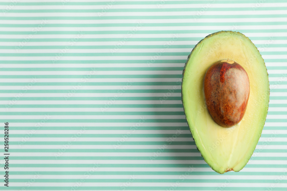Ripe cut avocado on color background, space for text