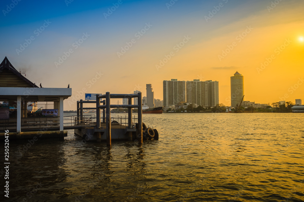 Landscape view of Chao Phraya river at Bang Krachao district pier during sunset  with hi-rise building and blue sky background. Peaceful river pier in Bangkok, Thailand.