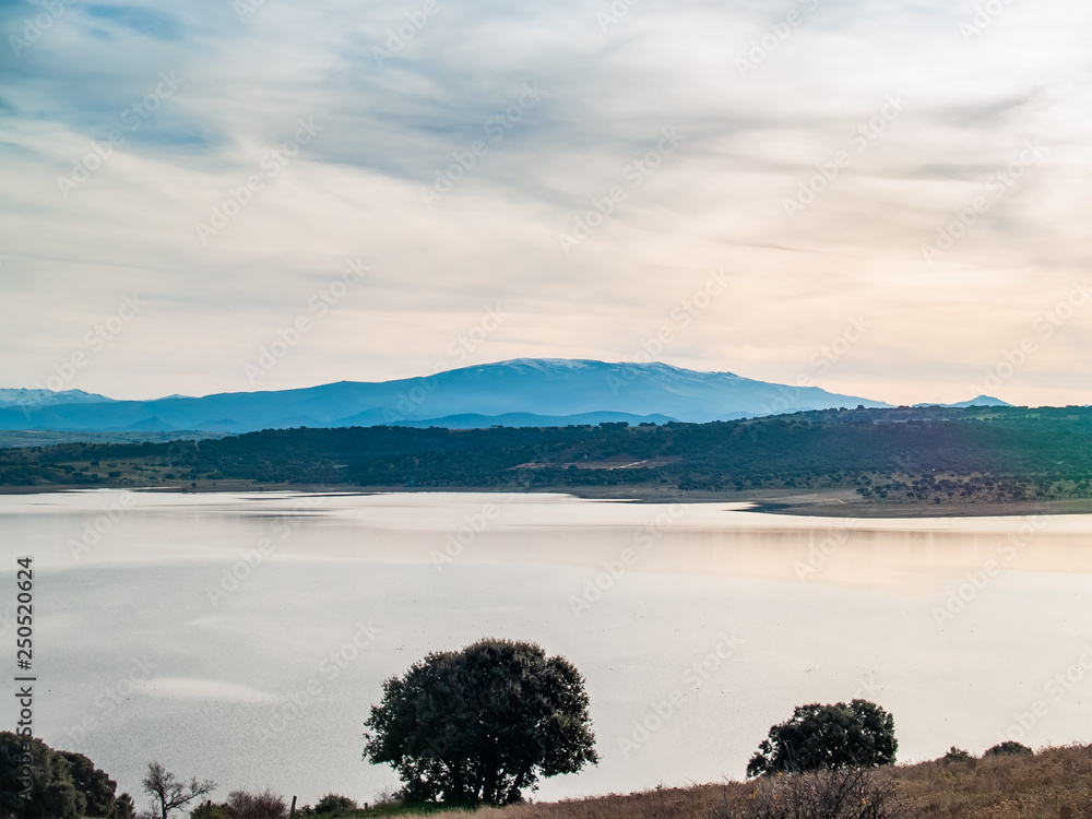 Landscape of a reservoir and mountains in a day with fog and clouds and birds swimming and flying in in La Maya Reservoir (Salamanca)