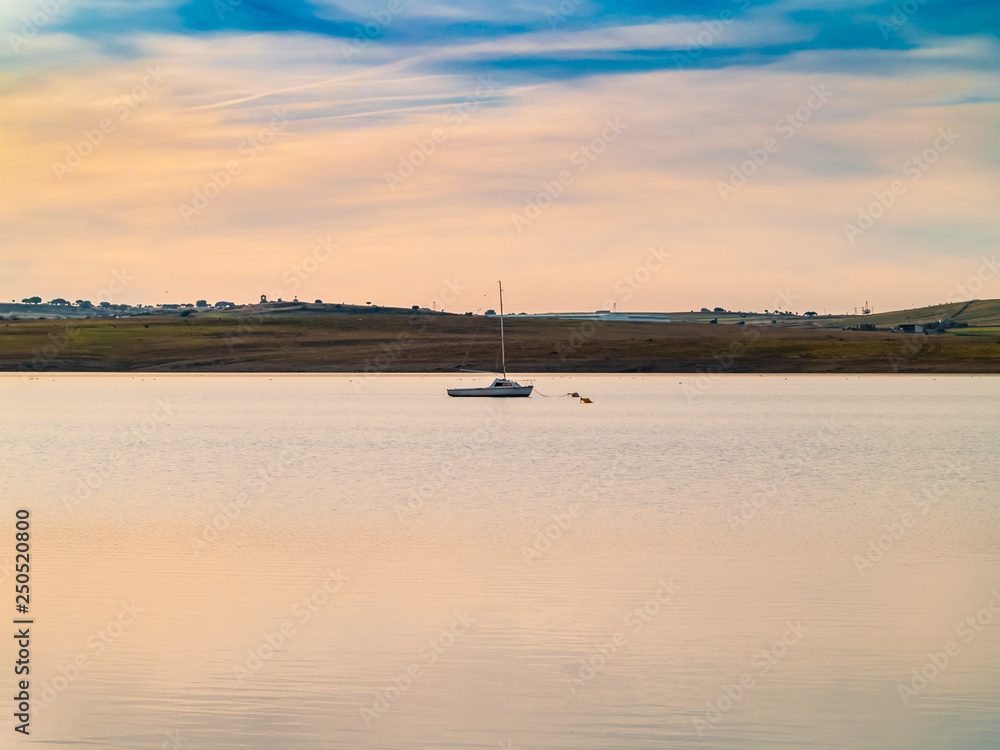 Boats on a lake at sunset, moored with a buoy and calm water in the reservoir of La Maya (Salamanca)