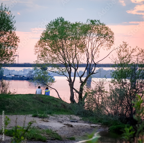 Romantic cople on the river bank, sunset