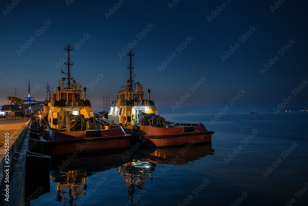 Dark view of two fishing boats mooring on pier in Batumi harbour. Night is coming and the sea is calm.