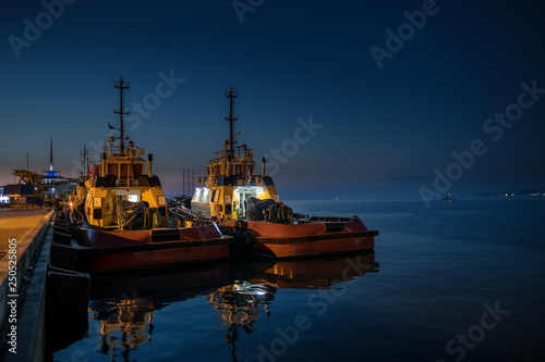 Dark view of two fishing boats mooring on pier in Batumi harbour. Night is coming and the sea is calm.