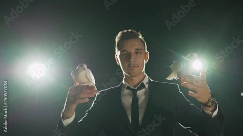 Male magician with white pigeon on dark background