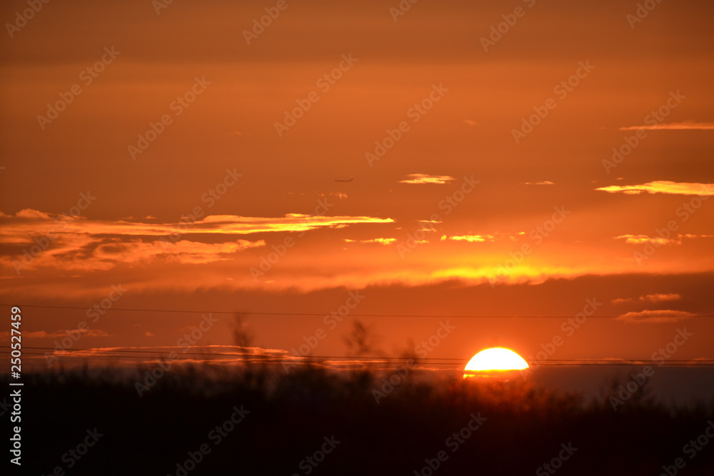 Beautiful orange sunset with sun on horizon of dark landscape