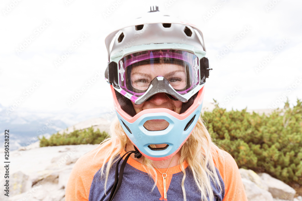 Close-up portrait of woman wearing helmet while standing on mountain against cloudy sky Close-up portrait of woman wearing helmet while standing on mountain against cloudy sky