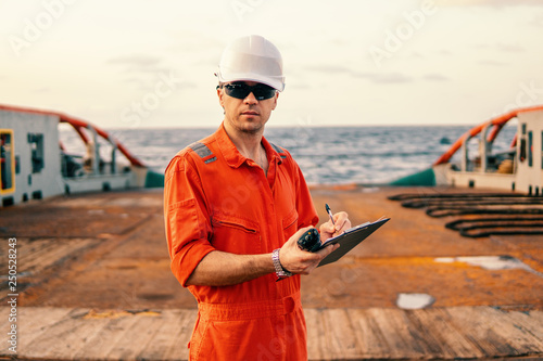 Marine chief officer or chief mate on deck of ship or vessel. He fills up checklist. Ship routine paperwork photo