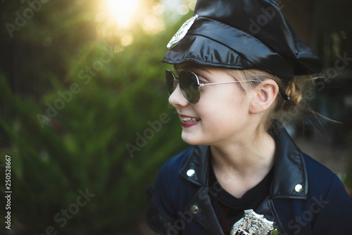 Obraz na plátně Close-up of smiling girl in police costume wearing sunglasses while standing aga