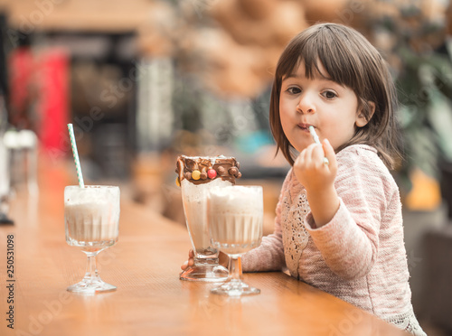 Charming Funny little girl drinks a milkshake