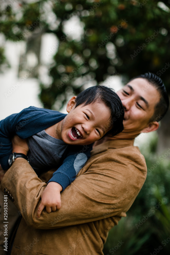 Low angle view of father carrying happy son while standing against trees in Balboa Park Low angle view of father carrying happy son while standing against trees in Balboa Park