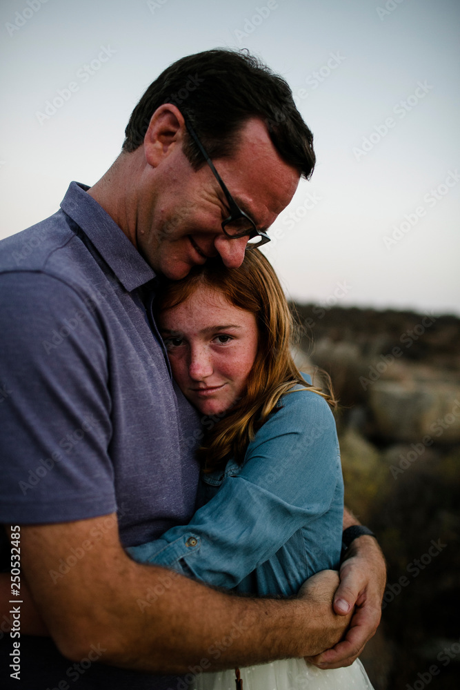 Portrait of daughter embracing father while standing on field during sunset Portrait of daughter embracing father while standing on field during sunset