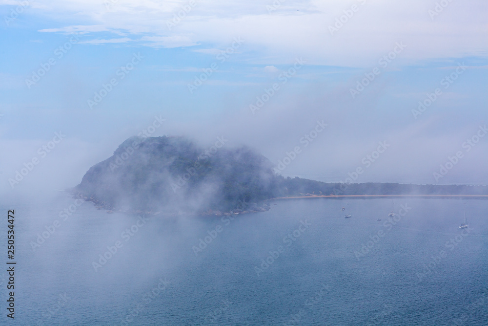 Low clouds above the ocean hiding moored sailboats and Barrenjoey lighthouse in Sydney, Australia Low clouds above the ocean hiding moored sailboats and Barrenjoey lighthouse in Sydney, Australia