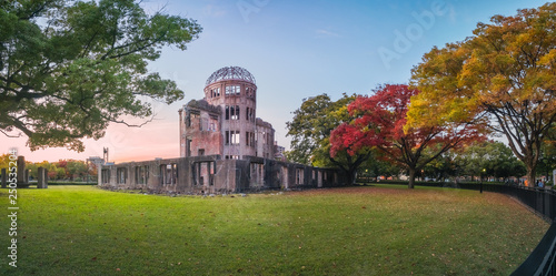 The Atomic Bomb Dome Panorama in Hiroshima and the surounding garden in autumn at sunset on the side of Motoyasu River in Japan, with the Peace Memorial Park on the left in the background. photo