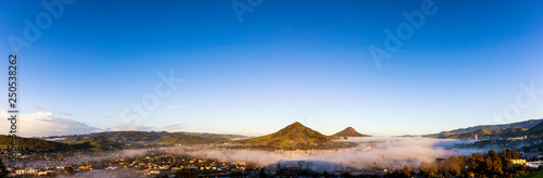 Sunrise panorama of City with Fog and Mountains