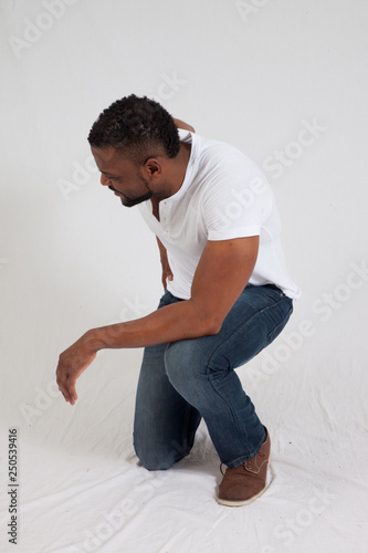 Happy black man kneeling in a white shirt © Allen Penton
