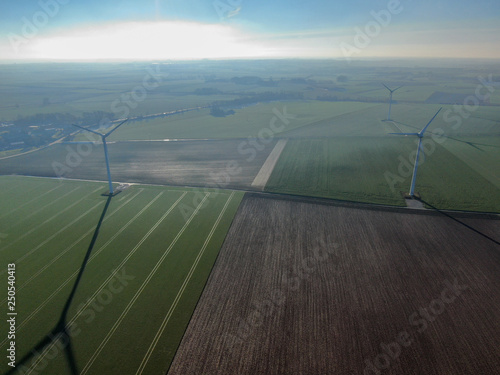 Aerial view of wind turbines and agricultural fields on a beautiful blue winter day - Energy Production with clean and Renewable Energy - aerial shot, analog image style