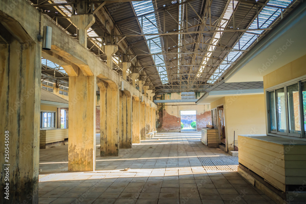 The ruins of an old abandoned factory. Perspective of abandoned warehouse from the inside with translucent roof and concrete structure.