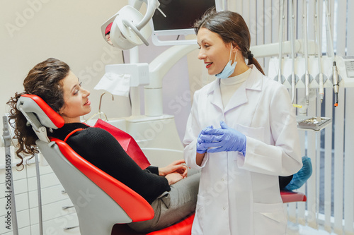 A female dentist speaks with a patient. Dentist carrying the model in hand. During this doctor is wearing a glove mask.
