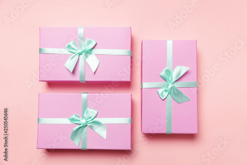 Christmas New Year birthday valentine celebration present romantic concept. Three small gift boxes wrapped pink paper isolated on pink pastel colorful trendy background. Flat lay top view copy space photo