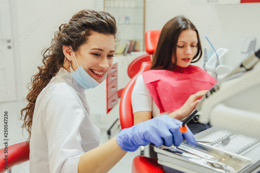 Young woman sitting in a dental chair for appointment of a doctor. During this time she was very worried about fear, then looking into the phone. Young woman sitting in a dental chair for appointment of a doctor. During this time she was very worried about fear, then looking into the phone.