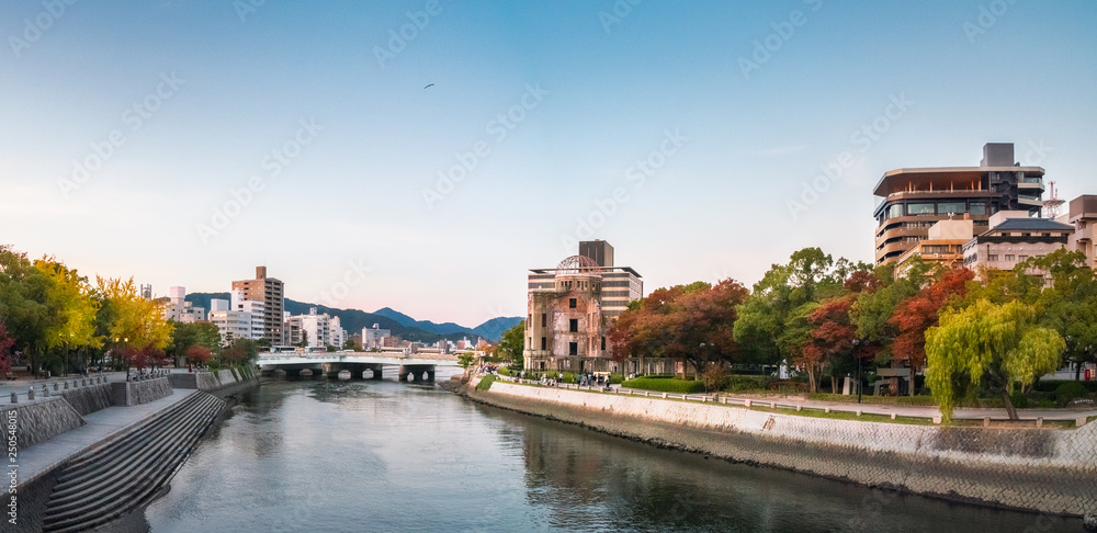 Naklejka premium Hiroshima Cityscape at sunset on the side of Motoyasu River in Japan with the Peace Memorial Park on the left hand side and the ruin of the Atomic Bomb Dome on the right.
