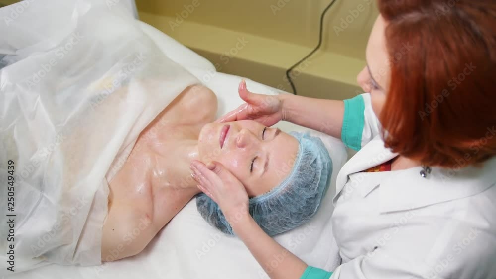 A face massage treatment in cosmetology clinic. The doctor smears the special oil on the face A face massage treatment in cosmetology clinic. The doctor smears the special oil on the face