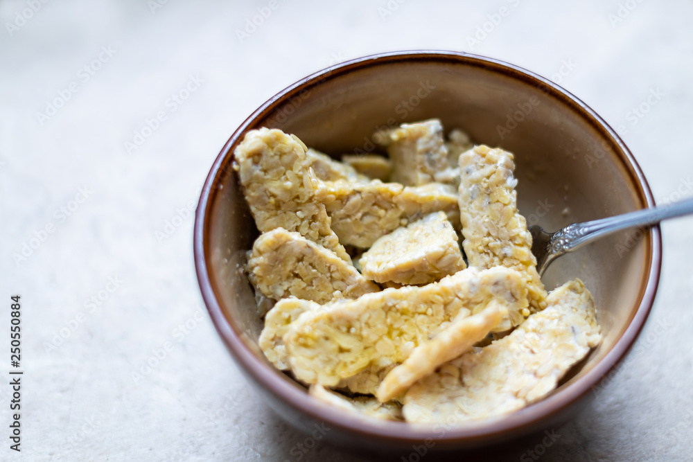 Closeup of bowl with sliced cut tempeh fermented soybeans on table cooking ingredient Closeup of bowl with sliced cut tempeh fermented soybeans on table cooking ingredient