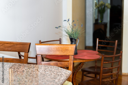 Wooden brown kitchen counter and granite countertop bar with two chairs in small apartment stool interior design with table and corridor hall