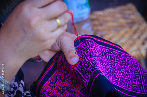 Close up hand of Hmong woman is sewing traditional tribal clothes with sewing needle and thread at Doi Pui’s Hmong ethnic hill-tribe village, Chiang Mai, Thailand. photo