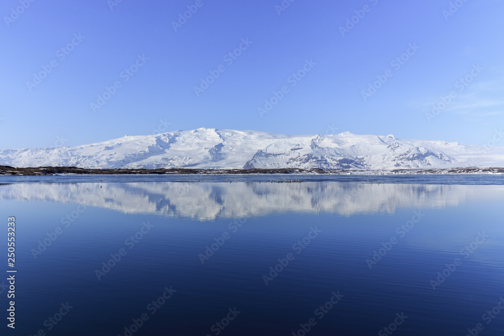 Snow covered mountain and its reflection in a lake