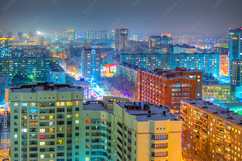 Beautiful top view of the city. Colorful street lighting of the night metropolis. Many high-rise buildings. Cold winter weather. There is snow on the roofs of houses. Novosibirsk, Siberia, Russia.