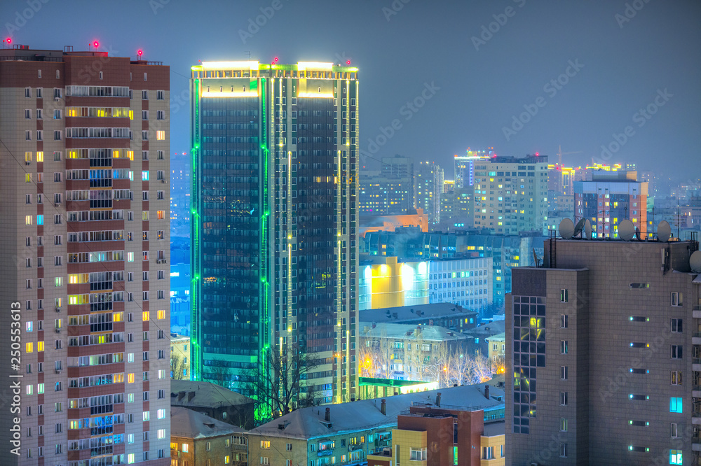Beautiful top view of the city. Colorful street lighting of the night metropolis. Many high-rise buildings. Cold winter weather. There is snow on the roofs of houses. Novosibirsk, Siberia, Russia. Beautiful top view of the city. Colorful street lighting of the night metropolis. Many high-rise buildings. Cold winter weather. There is snow on the roofs of houses. Novosibirsk, Siberia, Russia.