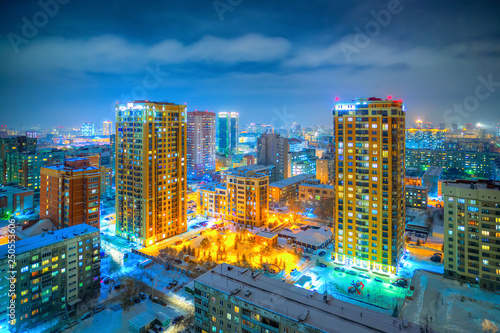 Beautiful top view of the city. Colorful street lighting of the night metropolis. Many high-rise buildings. Cold winter weather. There is snow on the roofs of houses. Novosibirsk, Siberia, Russia.