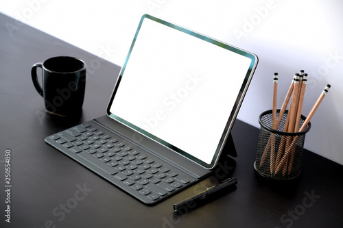 Tablet with smart keyboard case with blank screen on dark wood table