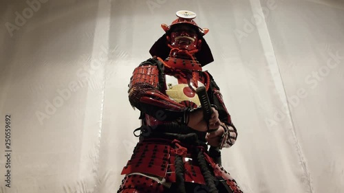 samurai in red helmet doing exercises with a katana sword