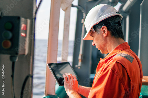 Bild auf Leinwand Marine chief officer or captain on deck of vessel or ship watching digital tablet