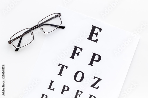 Eye examination. Eyesight test chart and glasses on white background top view