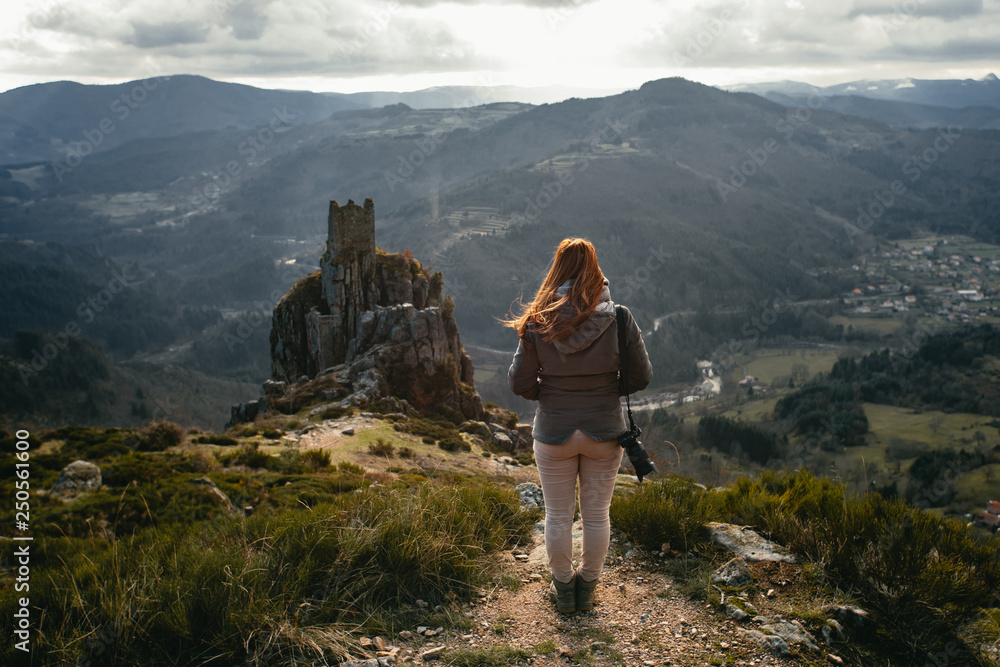 Fototapeta premium young woman watching medieval tower ruins built on a rock