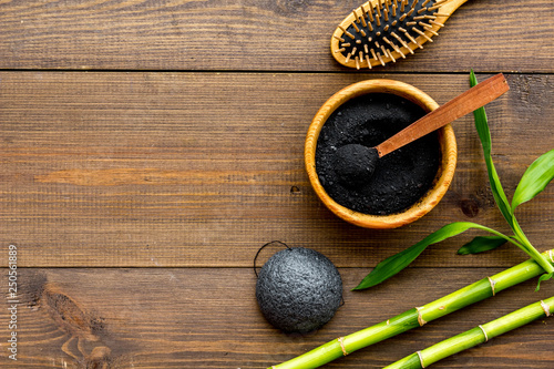 Skin cleansing and detox. Bamboo charcoal powder cosmetics on dark wooden background top view copy space